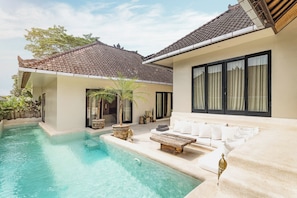 Un área de piscina moderna con una silla de descanso y una mesa de madera.