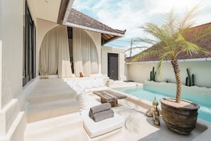A poolside area with a seating arrangement, a small pool, and a palm tree. - 2-bedroom Villa private pool (Badung)