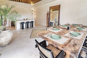 Un comedor con mesa de madera dispuesta para cuatro personas, rodeada de sillas tejidas.