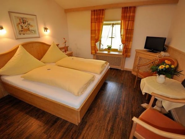 Ein Hotelzimmer mit einem Bett, einem Schreibtisch, einem Stuhl, einem Fernseher und einem Fenster mit Vorhängen.