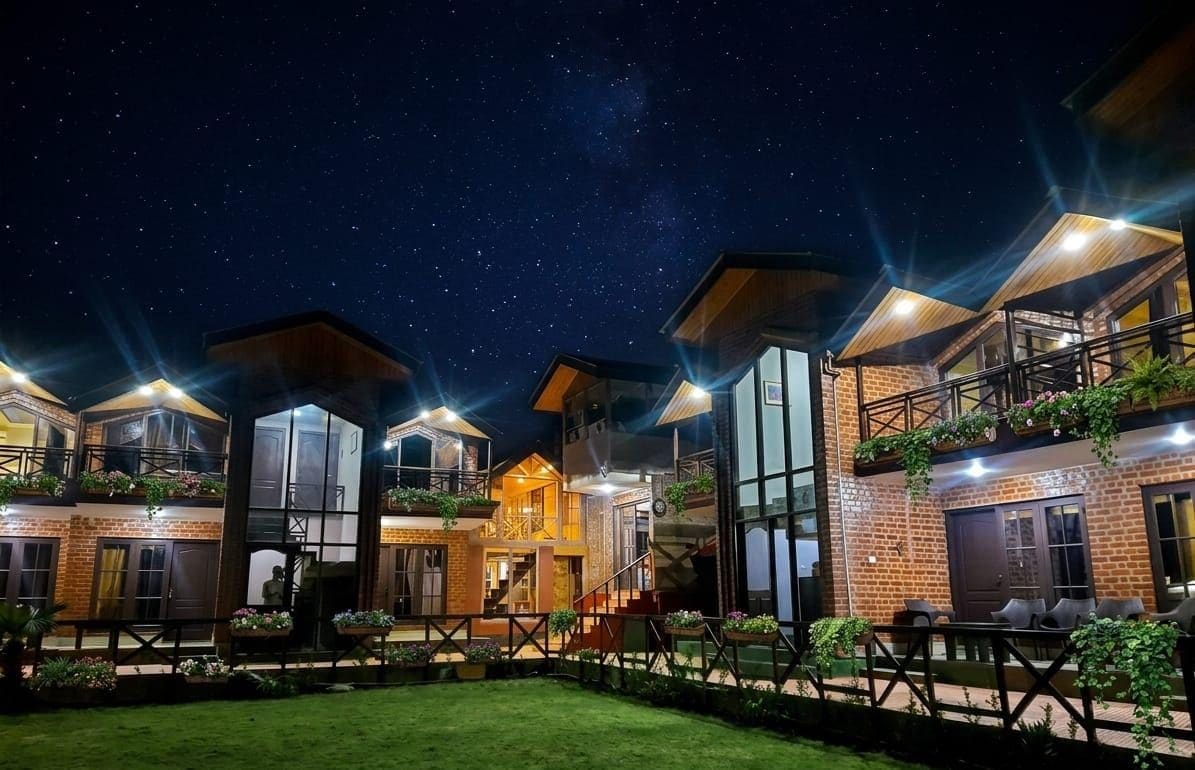 Un hotel de varios pisos con patio interior, amplias ventanas y mobiliario exterior.
