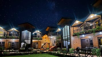 Un hotel de varios pisos con patio interior, amplias ventanas y mobiliario exterior.