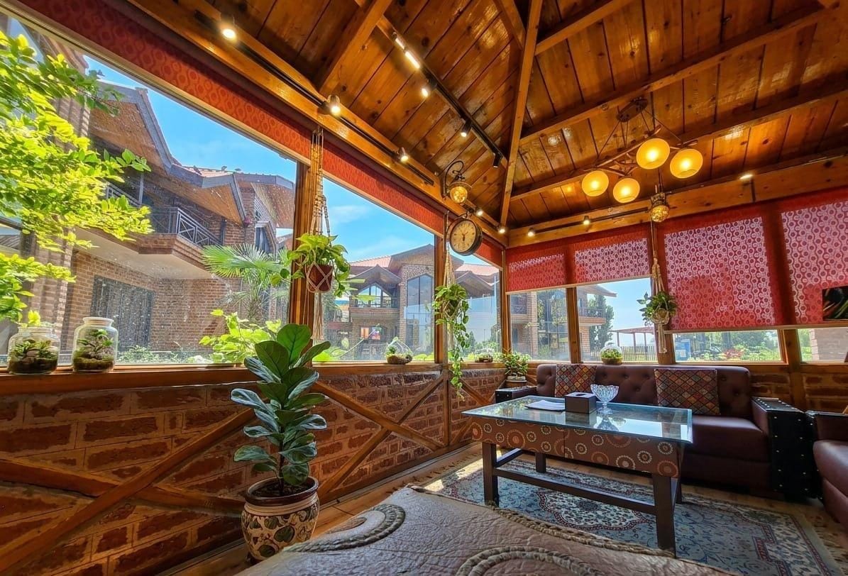 Un interior acogedor con techo de madera, ventanas amplias y una zona de estar con una mesa.