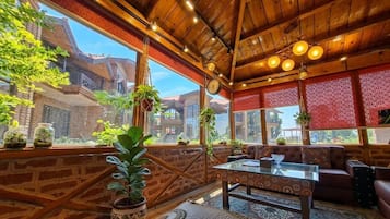 Un interior acogedor con techo de madera, ventanas amplias y una zona de estar con una mesa.
