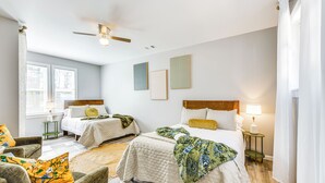 Camera da letto con due letti, una ventola a soffitto e opere d'arte alle pareti.