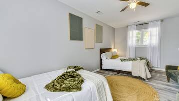 A bedroom with two beds, a ceiling fan, and a window with curtains.