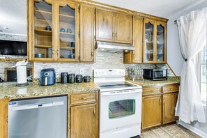 A kitchen with wooden cabinets, a stove, a microwave, and a dishwasher.