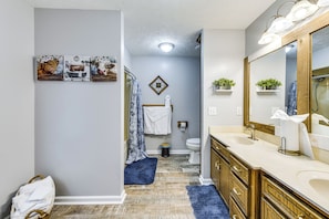 A bathroom with a wooden vanity, a large mirror, and a shower area. - Game Day Hideaway! Spacious Opelika Escape (Opelika)