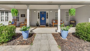 Una casa con portico, piante in vaso e una porta blu.