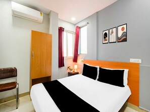 Ein Hotelzimmer mit einem Bett, einem Holzschrank, einem Fenster mit Vorhängen und Wandbildern.