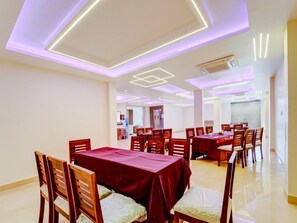 A dining area with multiple tables and chairs, a modern ceiling design with integrated lighting, and a clean, minimalist aesthetic.