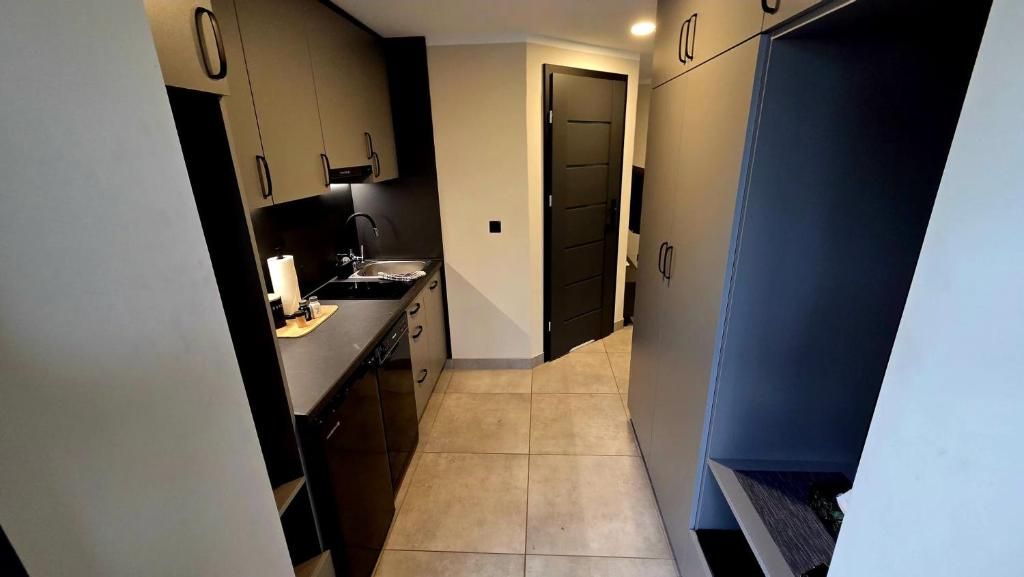 A compact kitchen with a sink, cabinets, and a door leading to another room.