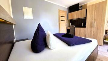 A bedroom with a bed, pillows, a wardrobe, and a nightstand.