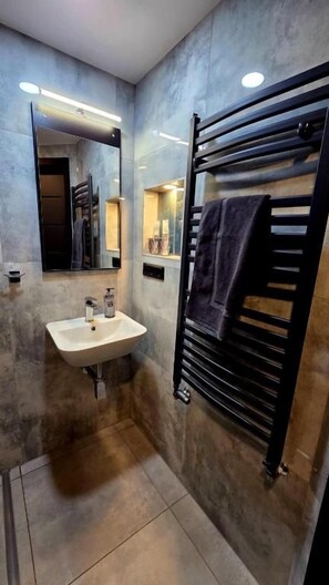 A modern bathroom with a sink, mirror, towel rack, and tiled walls. - Pension Schwarze Pumpe (Spremberg)