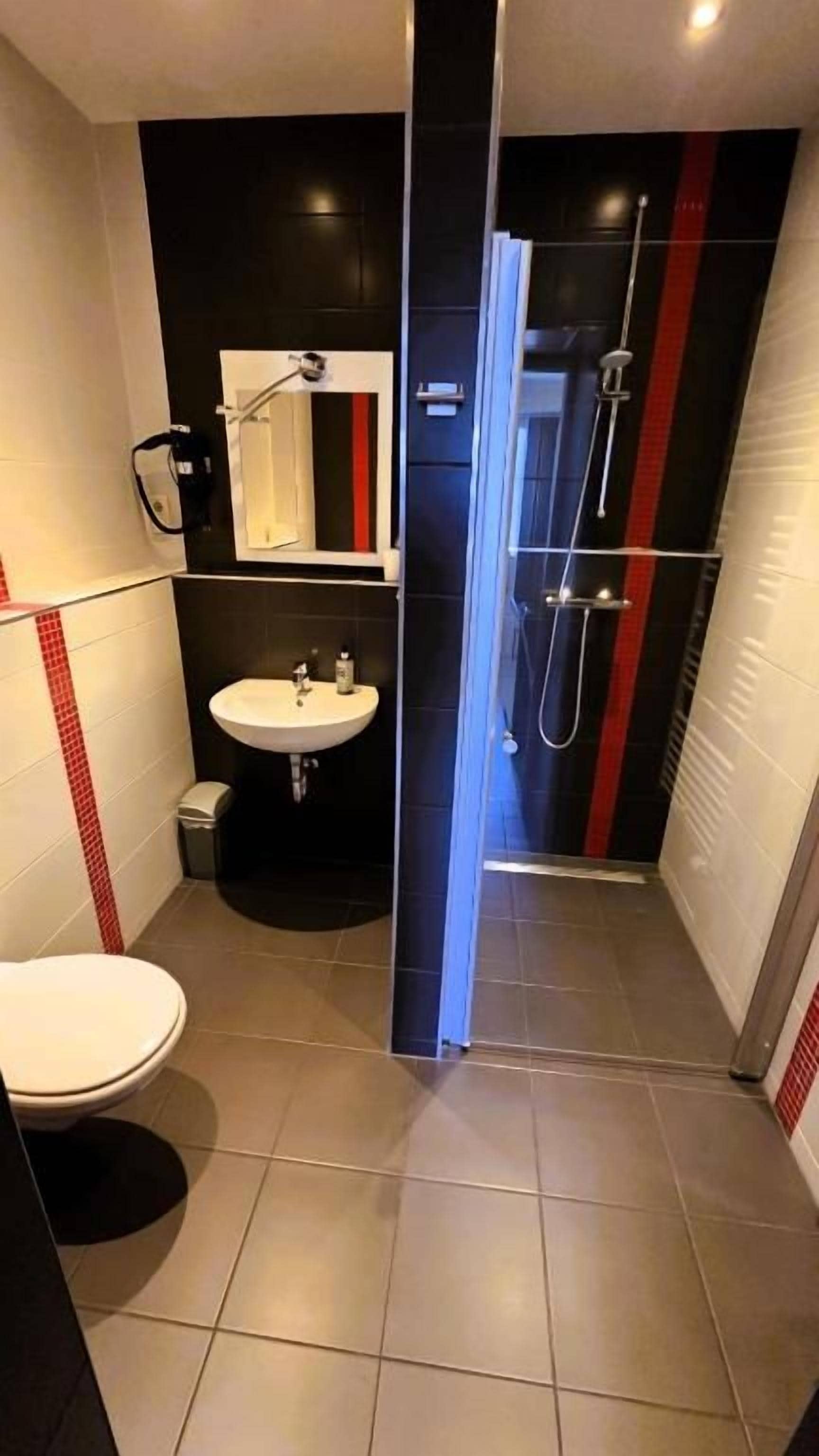 Une petite salle de bain comprenant des toilettes, un lavabo et un espace douche.