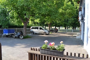 A parking area with a car and a motorcycle, surrounded by trees and a fence.