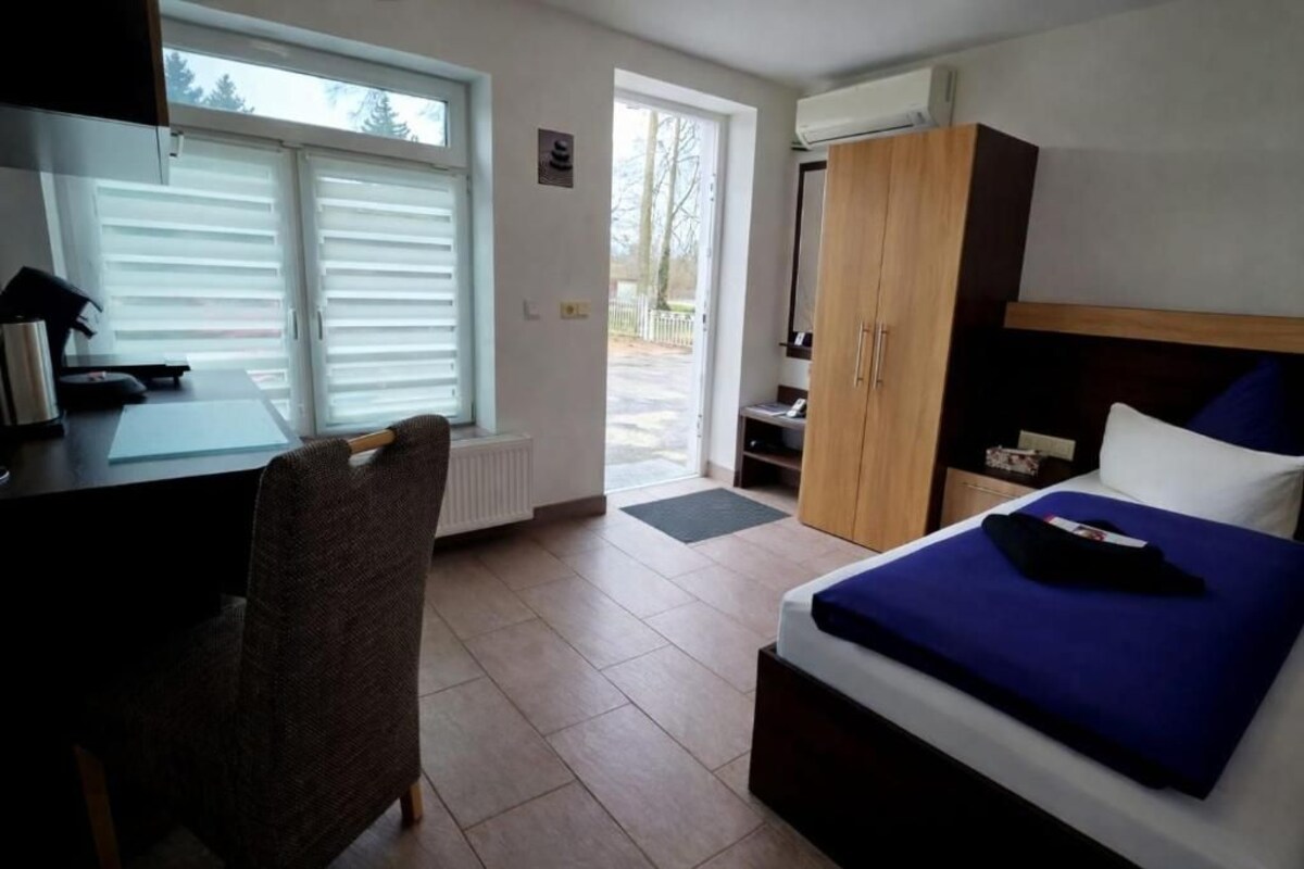 A room with a bed, a desk, a chair, a wardrobe, and a window.