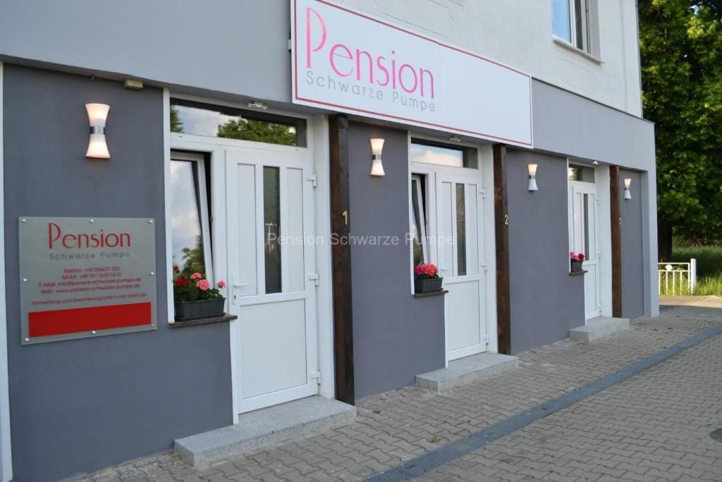 A building with a sign reading 'Pension Schwarze Pumpe' and a smaller sign below it with contact information.