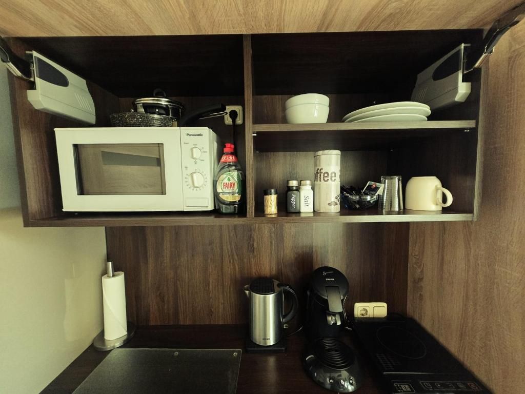 A kitchen with a microwave, coffee maker, and a kettle on the countertop.