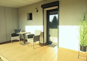 A balcony with a table and two chairs, a potted plant, and a door leading outside. - Pension Schwarze Pumpe (Spremberg)