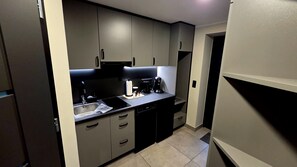 Cocina compacta con lavamanos, estufa y cafetera.