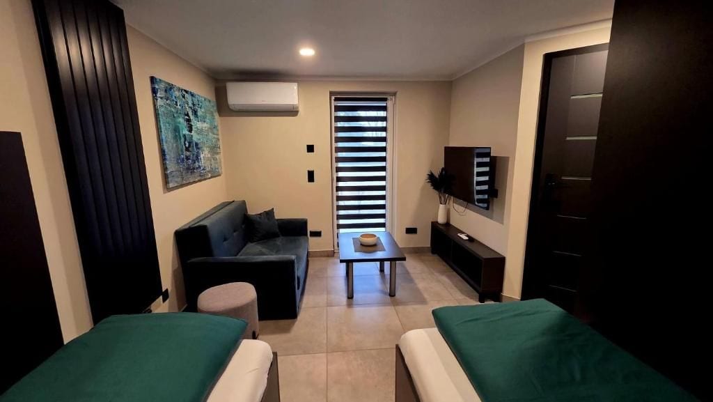 A compact living space with a sofa, a small table, a TV, and a door.