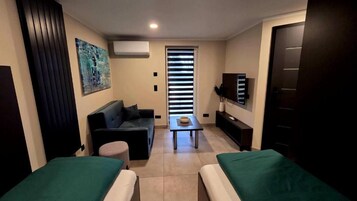 A compact living space with a sofa, a small table, a TV, and a door.
