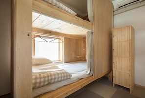 A bunk bed with a wooden headboard, a small window with curtains, and a wooden wardrobe. - saino tsuno guesthouse (Ueda)