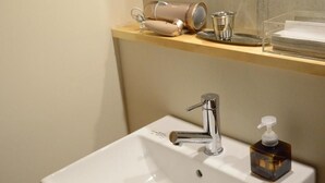 A bathroom sink with a chrome faucet, a soap dispenser, and a cup on the countertop. - saino tsuno guesthouse (uedashi chuuou)