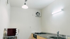 A compact kitchen with a built-in dishwasher, a stove, and a sink. - saino tsuno guesthouse (uedashi chuuou)