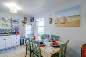 Una cocina con comedor, un refrigerador y un cuadro con una playa.