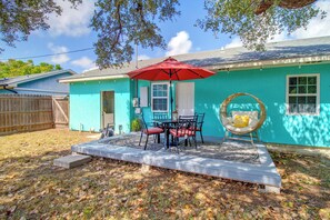 A house with a blue exterior, a patio with a table and chairs, and a red umbrella. - Corner Cottage - Just Minutes from the Water (Aransas Pass)