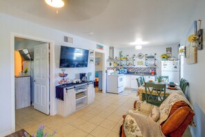 A compact living space with a kitchen, dining area, and a television mounted on the wall. - Corner Cottage - Just Minutes from the Water (Aransas Pass)