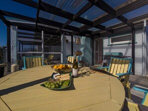 Eine Terrasse im Freien mit einem runden Tisch, gedeckt für eine Mahlzeit, umgeben von Stühlen.