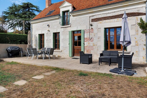 A building with a patio area featuring outdoor furniture and a barbecue grill.