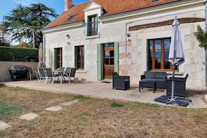 Un edificio con un patio amueblado al aire libre y una parrilla.