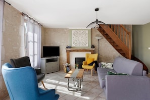 A living room with a TV, seating, a fireplace, and a staircase. - Holiday Home 'Gîte De Camille - Gîte Du Cher' with Wi-Fi (Châtillon-sur-Cher)