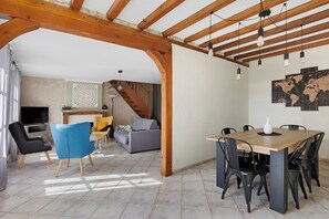 Amplia sala de estar con techo de madera, una mesa de comedor con sillas, un sofá y un televisor.