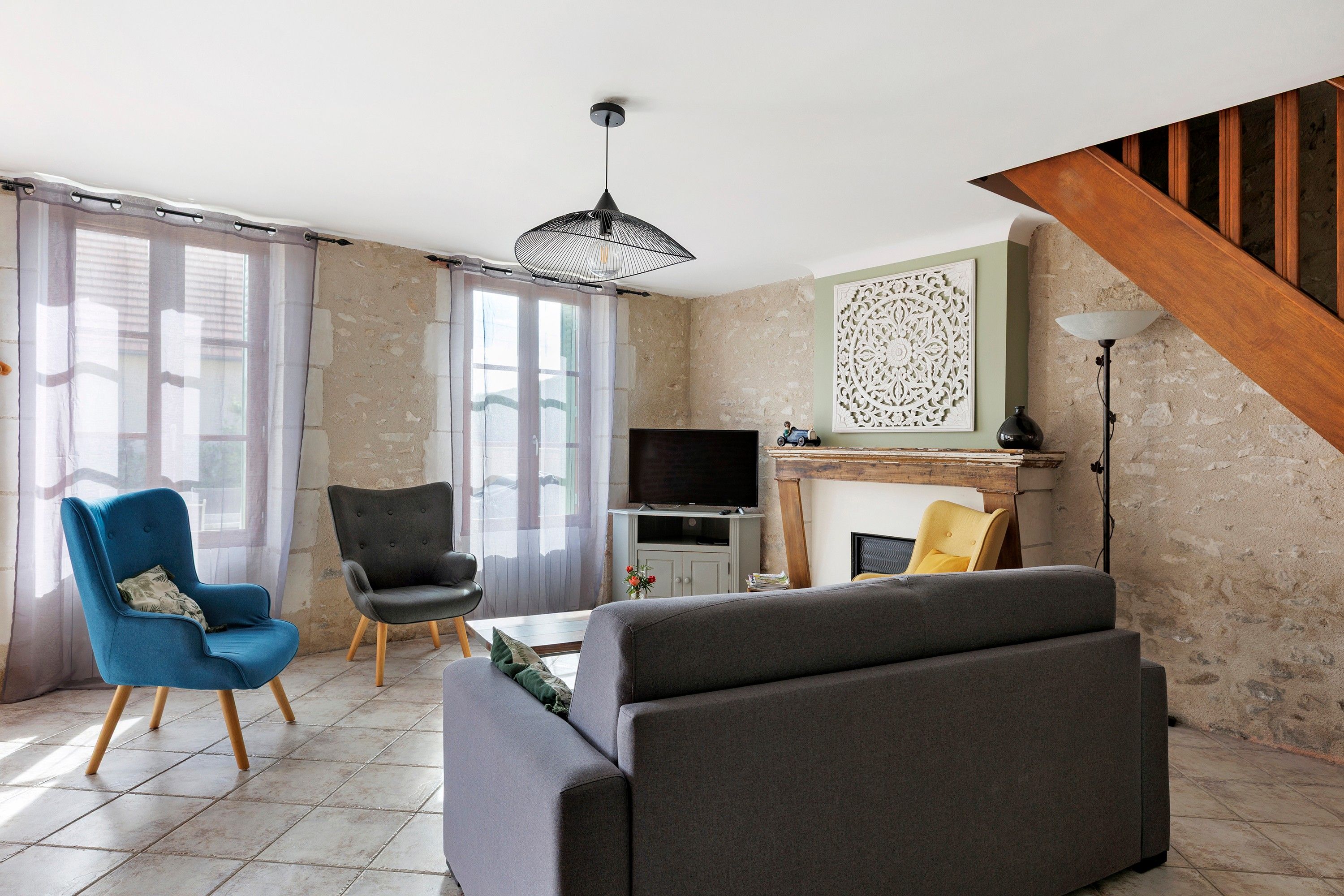 Een woonkamer met een bank, stoelen, een televisie en een open haard.