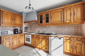 A kitchen with wooden cabinets, a microwave, a stove, and a dishwasher. - Holiday Home 'Gîte De Camille - Gîte Du Cher' with Wi-Fi (Châtillon-sur-Cher)