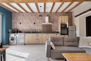 Una cucina compatta con una parete in mattoni, mobili in legno e un forno a incasso.