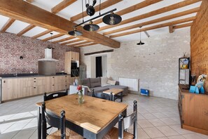 Una cucina moderna con pareti in mattoni a vista, travi in legno e un'area pranzo con tavolo e sedie di legno.