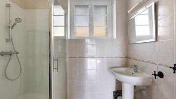 Une salle de bain avec une douche, un lavabo et une fenêtre.