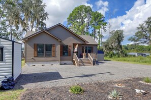 A single-story house with a front porch, a gravel driveway, and a small garden area with plants. - Waterfront Interlachen Retreat w/ Dock on Lake Ida (Interlachen)