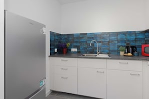 A kitchen with white cabinets, a stainless steel sink, and a blue-tiled backsplash. - Warsaw | Złota 11 | Comfortable Apartment | Downtown (Warszawa)