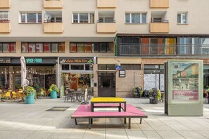 A street with outdoor seating, a cafe, and a shop with a sign that reads 'VEGE FOOD'. - Warsaw | Złota 11 | Comfortable Apartment | Downtown (Warszawa)