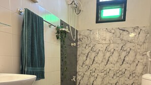 A bathroom with a white sink, a toilet, a shower with a handheld showerhead, and a green light above the window. - Rock Hill Hotel  (Unawatuna)