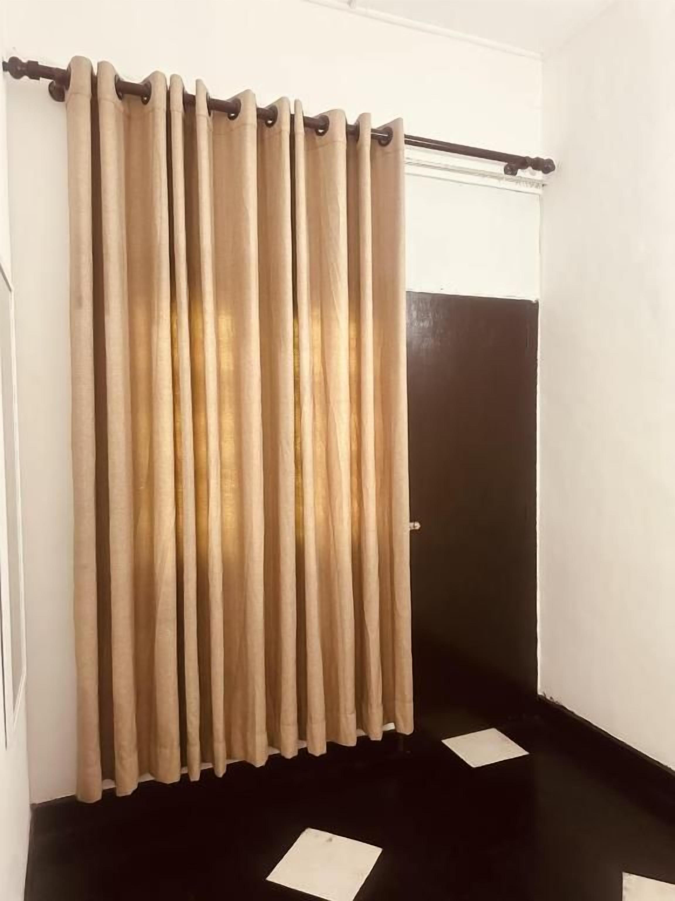 A room with a black floor, a beige curtain, and a white door.
