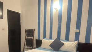 A hotel room with a bed, a chair, a desk, and a wall with vertical stripes. - Rock Hill Hotel  (Unawatuna)