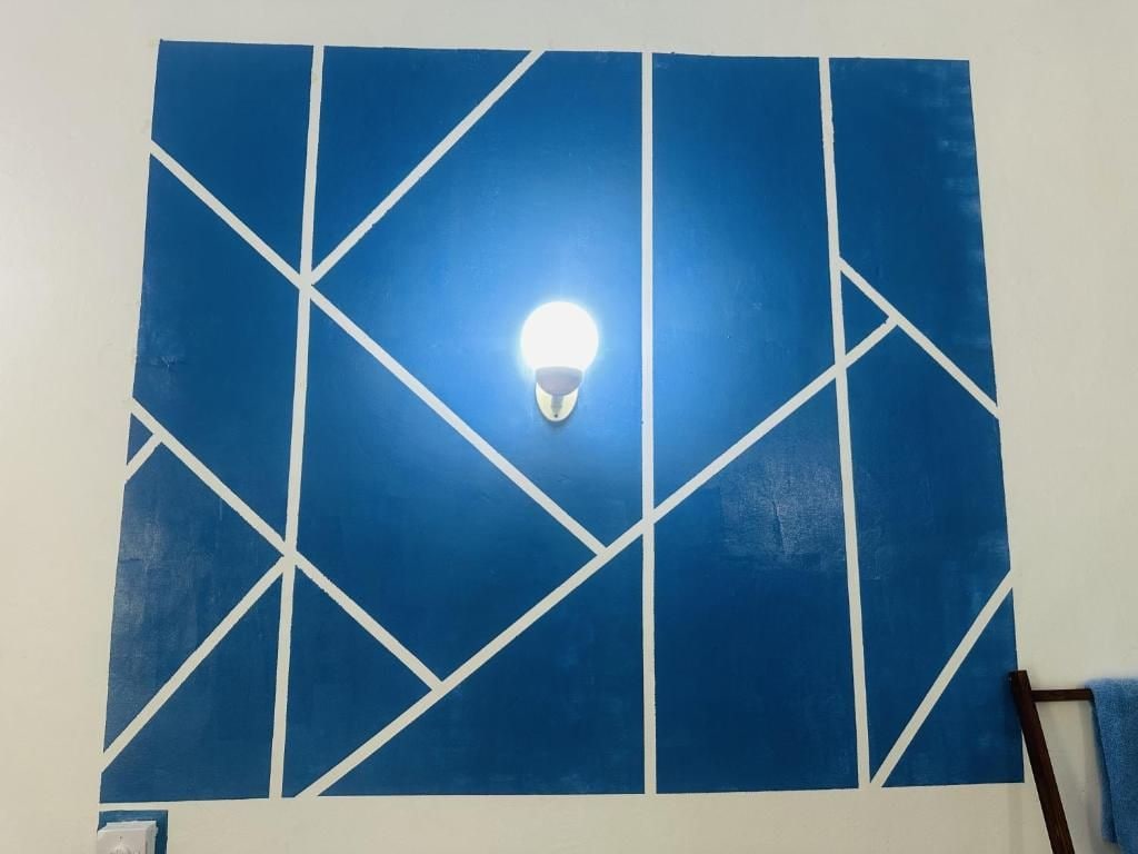 A room with a geometric blue wall design and a light fixture.